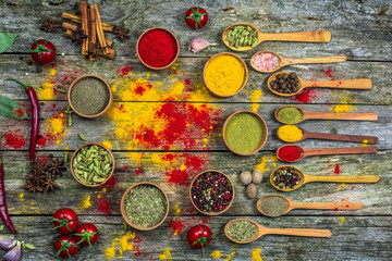 Spices in a wooden bowl, fresh tomatoes and hot red pepper lie on an old table.