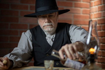 1885 old west cowboy sitting in a saloon pouring whiskey tight shot