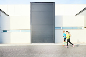 Fototapeta na wymiar man and woman running alongside a modern building
