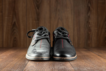 Black shoes one clean second dirty on a wooden background. The concept of shoe shine, clothing care, services.