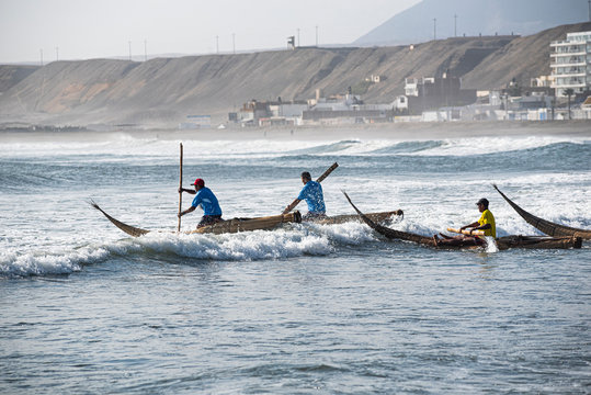 Fishermen entering the sea in traditional fishing boats called: Caballitos de Totora.