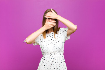 red head pretty woman covering face with both hands saying no to the camera! refusing pictures or...
