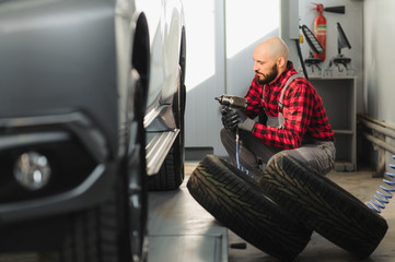 Man repairing a car wheel in a garage