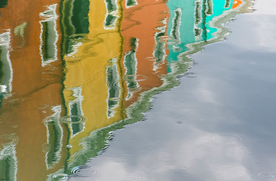 The colorful houses of Burano are reflected in the waters of the canals on a rainy spring afternoon, Venice, Italy, Europe