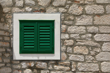 Stone house with window with shutters. A bunch of wooden window shutters pattern on white stone wall. Naked worn wooden and plain painted shutters. Hipster loft wallpaper.