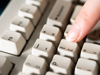 Female forefinger pushes LEFT SQUARE BRACKET button. Close-up