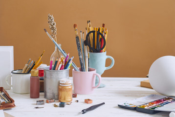 Artist studio with paper and utensils. Workspace of designer illustrator with lots of materilals and equipement. Paints, brushes and pencils.