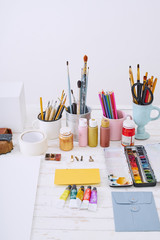 Artist studio with paper and utensils. Workspace of designer illustrator with gypsum shapes, pencils, brushes and paint bottles. Freelance creative concept