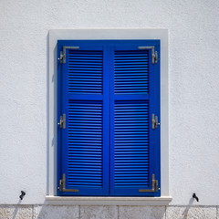 Stone house with window with shutters. A bunch of wooden window shutters pattern on white stone wall. Naked worn wooden and plain painted shutters. Hipster loft wallpaper.