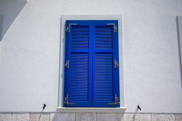 Stone house with window with shutters. A bunch of wooden window shutters pattern on white stone wall. Naked worn wooden and plain painted shutters. Hipster loft wallpaper.