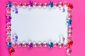 Valentine's day frame on pink background made of pebbles in the shape of a heart with white space.