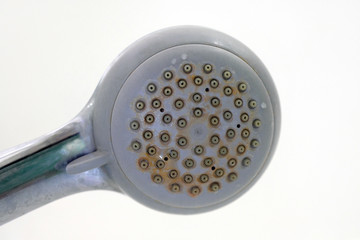 Old shower head with plaque. Dirty plastic shower head. Limescale coating on plumbing.