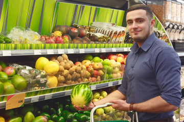 Young man pick to buy dwarf watermelon in supermarket or grocery store