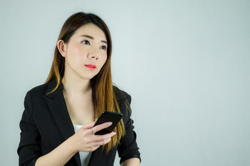 Portrait of beautiful asian business woman holding mobile phone and looking to space. Caucasian female model isolated on white background.