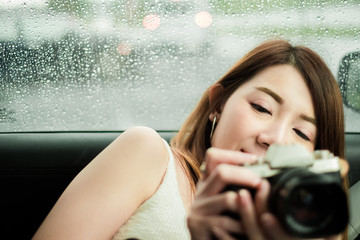 beautify asian woman with camera in car against rain drops background