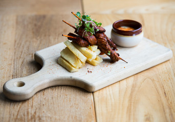 Anticucho Beef skewers with Yuka fries and tari sauce are shown on a table in a restaurant