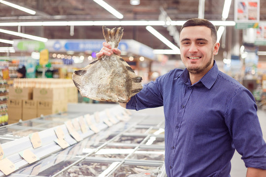 Man At The Grocery Store With Frozen Flounder Fish.