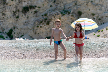 Little girl and boy holding hand on the beach