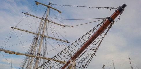 Rigging of a tall ship below a blue cloudy sky in sunlight in winter