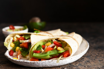 Mexican tortilla with beef, corn and vegetables with guacamole sauce on a concrete background.