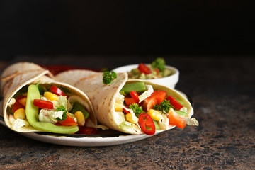 Mexican tortilla with beef, corn and vegetables with guacamole sauce on a concrete background.