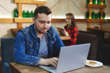 Young man sitting at the cafe and using laptop.