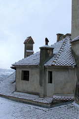 Detailed view of red tile roof in the snow. Ancient Bran Castle, also called Dracula's Castle. Famous touristic place and travel destination in Romania