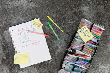 Mathematics book written by hand with arithmetic problems and pencil case, to do list, marble table