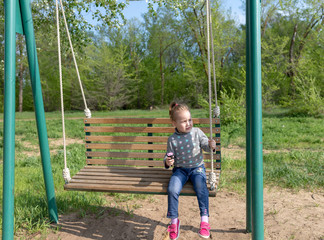 Child eating ice cream in a black waffle cone sitting on a swing