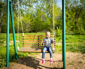 Child eating ice cream in a black waffle cone sitting on a swing