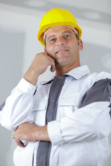 happy mature architect in helmet standing with crossed arms