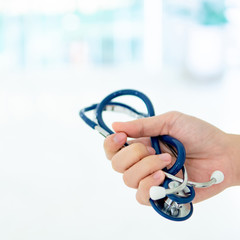 Global healthcare concept. Male doctor hand holding blue stethoscope in hospital or medical center. Equipment for medical exam or health check up.