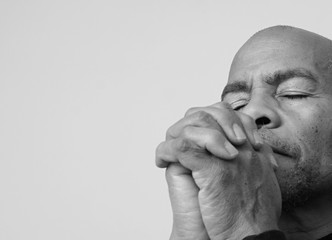 man praying to god with hands together Caribbean man praying with white background stock photo
