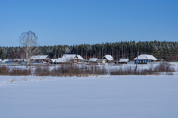 Fototapeta na wymiar Winter landscape on a Sunny day. View of the Russian village in the snow. Authentic Wooden houses 