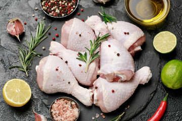 Raw uncooked chicken legs with spices and ingredients for cooking on cutting board