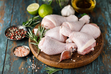 Raw uncooked chicken legs with spices and ingredients for cooking on cutting board