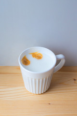 Beautiful white ceramic mug with aromatic tasty coffee, frothed snow-white milk stands on light wooden brown table, top view, side view. Free space. Cooking in coffee machine. Coffee eyes, smiley face