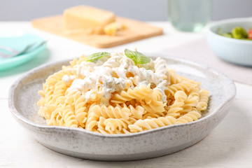 Tasty pasta with sauce and basil on white wooden table, closeup