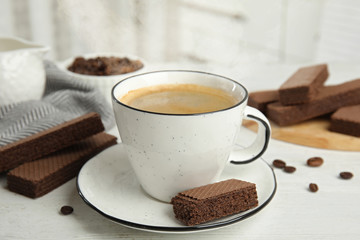 Delicious wafers and cup of coffee for breakfast on white wooden table