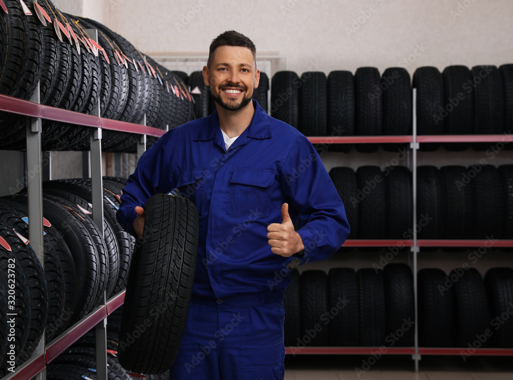 Canvas Prints Male mechanic with car tire in auto store