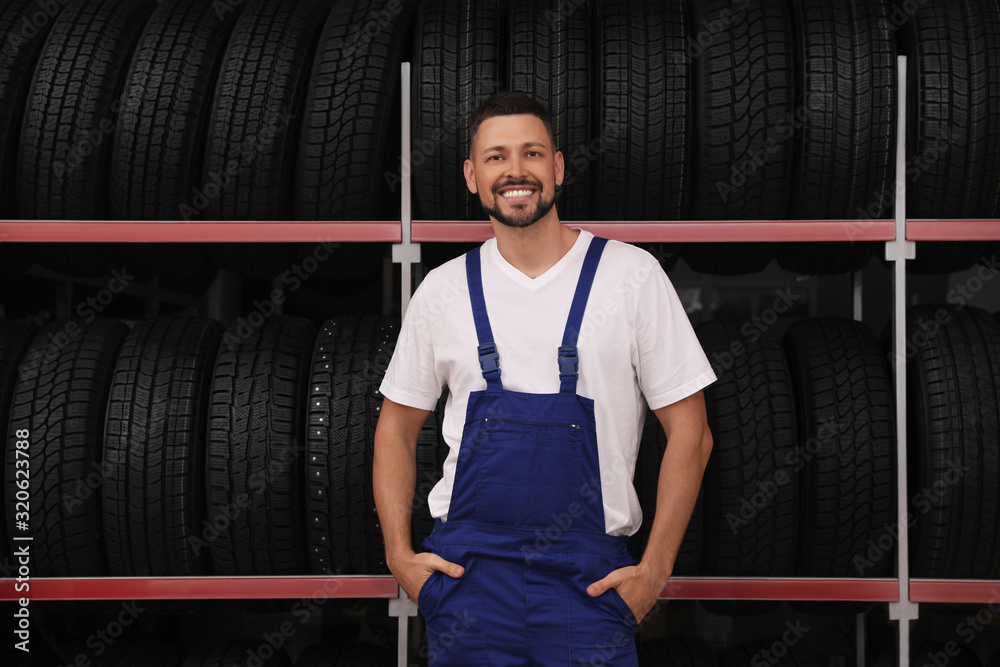 Sticker Male mechanic near rack with car tires in auto store