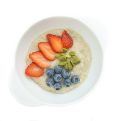 Vegan dish: oatmeal porridge with coconut milk, pumpkin seeds and fresh strawberries and blueberries. The concept of proper nutrition.