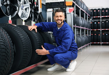 Obraz na płótnie Canvas Male mechanic with car tires in auto store