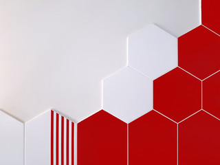 A background of bright red and white ceramic tiles in the shape of a hexagon that partially covers a white wall. Concept texture, background