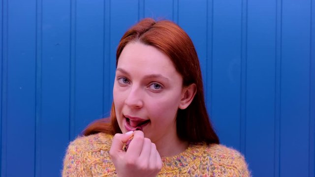 Young model putting on some makeup, using lipstick to color hel lips. Cosmetic concept.