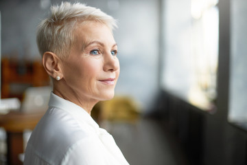 Close up profile shot of elegant short haired businesswoman wearing pearl earrings and stylish...