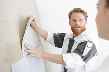 Obraz premium a handyman is fixing wallpaper
