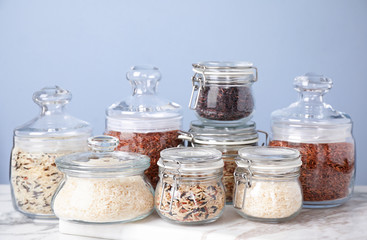 Brown and polished rice in jars on white marble table