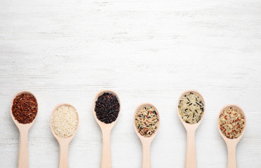 Flat lay composition with brown and polished rice on white wooden table. Space for text