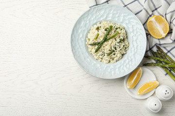 Delicious risotto with asparagus on white wooden table, flat lay. Space for text